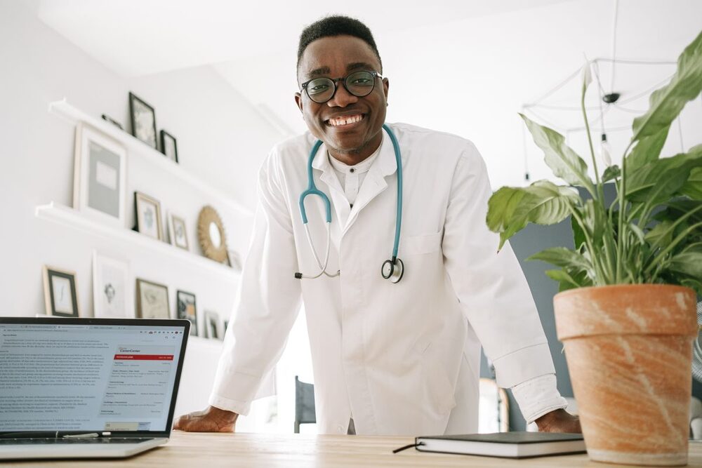 Médico sonriente trabajando con la historia clínica electrónica desde su portátil